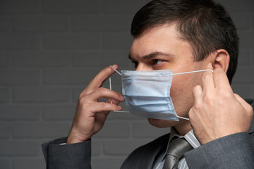 a man puts a mask on his face for antivirus individual protection - healthcare and medicine concept, prevention tips