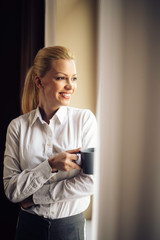 Young beautiful woman enjoying in coffee.Businesswoman working from a hotel room.