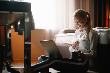 Businesswoman working from a hotel room. Beautiful woman working on lap top and drinking coffee.