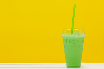 green beverage and green straw on yellow background