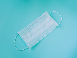 protective white medical mask on a blue background, a means of protection against the virus