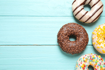 Delicious glazed donuts on blue wooden table, flat lay. Space for text
