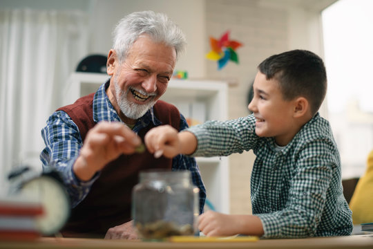 Grandpa and grandson saving money. Grandfather teaching grandchild how to save money.