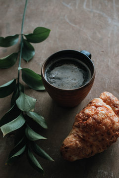 Cappuccino coffee and croissant on wooden background on the table. Perfect breakfast in the morning. Rustic candid style.