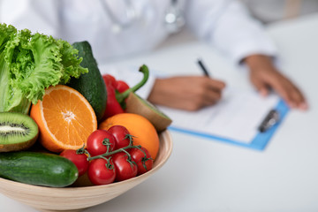 Bowl of fresh fruits and vegetables on dietologist workplace