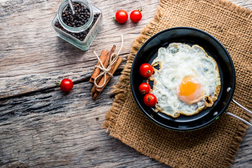 Fried eggs in pan with handle on wooden table