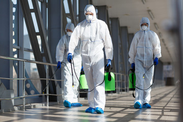 People in virus protective suits and mask disinfecting buildings
