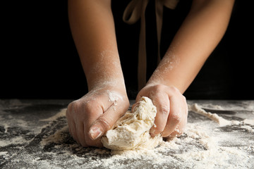 Woman kneading dough for pizza at grey table, closeup