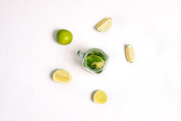 Cooking Mojito. Slices of lime and a glass cocktail jar on a white table.