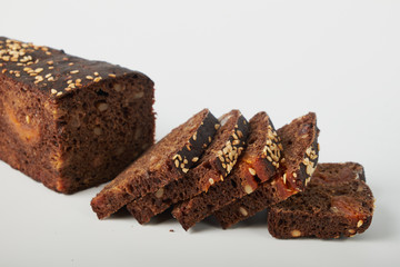 fresh bread with various seeds (pumpkin, dried apricots, flax, sunflower, sesame, prunes) is decorated with wheat ears isolated on a white background.