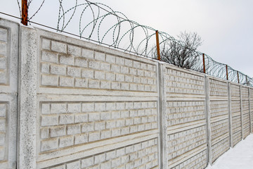Fototapeta premium Barbed wire on a concrete fence in winter