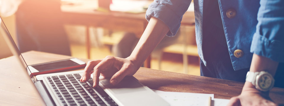 Woman working with laptop. Startup team in open space office. Wide screen. Panoramic
