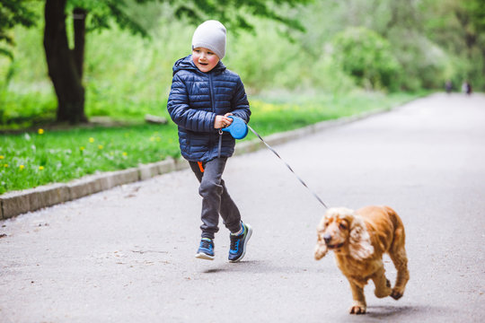 little kid with small brown dog running in city park