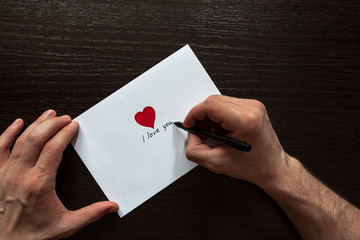 The process of signing a love envelope. The inscription "I love you and my heart".