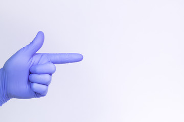 A gun sign by left man hand in a purple medical glove on a white background