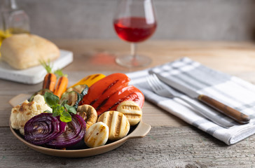 Fresh organic grilled vegetables bell pepper,mushrooms,broccoli,cauliflower,carrots seasoned with herbs on a round plate.