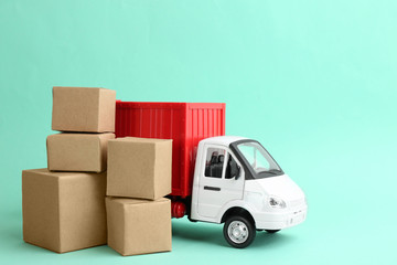 Truck model and carton boxes on turquoise background. Courier service