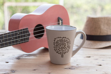 coffee cup and ukulele on wooden table