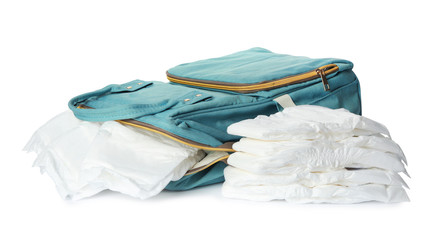 Backpack and disposable diapers on white background