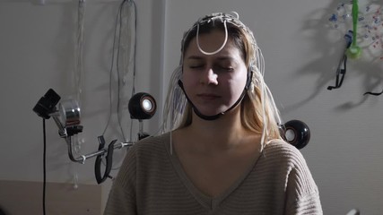 Electroencephalographic examination in clinic. Equipment for receiving brain EEG human. Female patient wired to EEG machine or electroencephalograph which produces graphical record of brain electrical