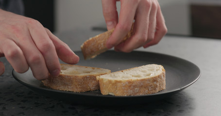 man hand put ciabatta slices on black plate