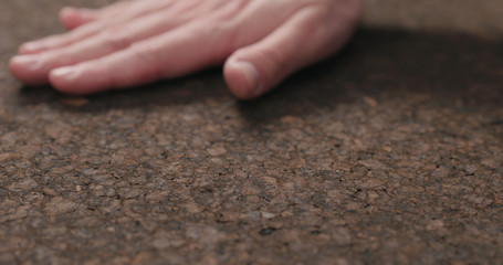 man hand touch dark cork surface with oil finish