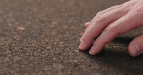man hand touch dark cork surface with oil finish