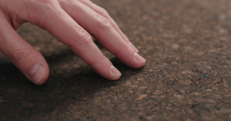 man hand touch dark cork surface with oil finish