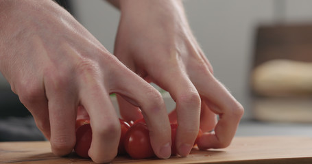 closeup man hands take cherry tomatoes from olive board