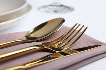 Stylish elegant cutlery set with napkin on white table, closeup