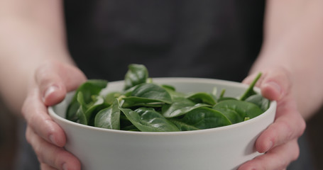 man show fresh spinach leaves in white bowl closeup