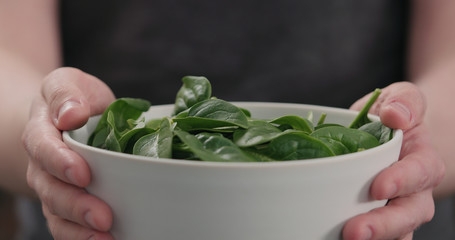 man show fresh spinach leaves in white bowl closeup