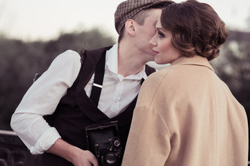 A large portrait of a young couple, a man kissing a woman, a man in the hands of a retro camera. Historical reconstruction