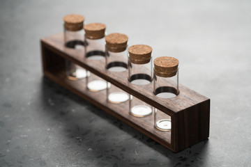walnut holder with glass tubes for spices on concrete surface