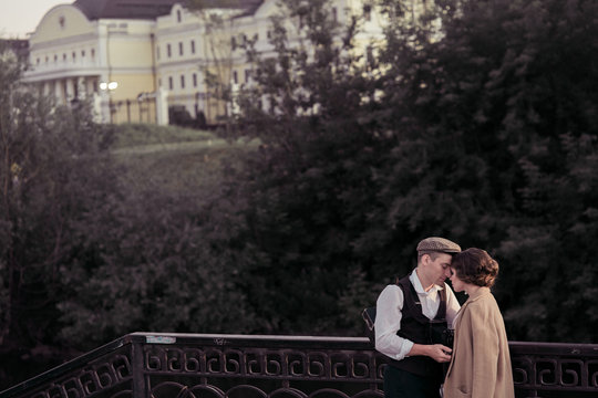 A young couple looks into each other's eyes, standing near the fence. Clothing in retro style. Historical reconstruction
