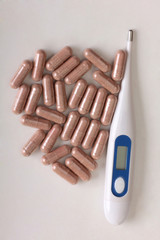 Pills and thermometer on a medical table