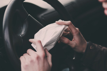 man drive car, holding in hands medical mask to protect from infection of viruses, pandemic, air pollution,