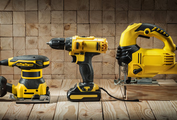 construction carpentry tools electric corded jigsaw cordless drill and wood sander on wooden...