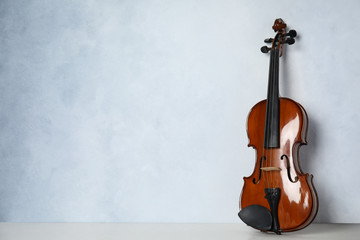 Beautiful violin on table near light blue wall. Space for text