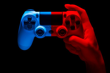 Hyman hand holding white video game gamepad in neon lights isolated on a black