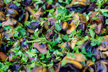 Top view of large portion of freshly cooked mussels and parsley on display for sale at a street food festival, ready to eat healthy seafood