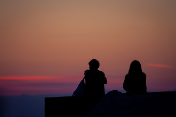 Fototapeta na wymiar silhouette of a young couple watching the sunrise over the sea