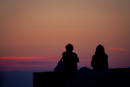 silhouette of a young couple watching the sunrise over the sea