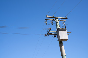 Electric pole under blue sky in rural, New Zealand.