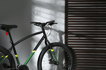 Modern black bicycle near grey wall indoors