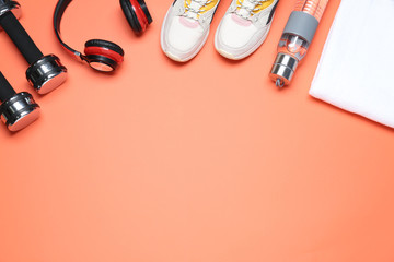 Flat lay composition with sport items on coral background, space for text