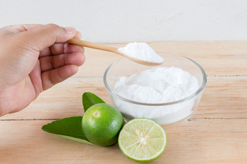 Baking soda in glass bowl and spoon on wooden background