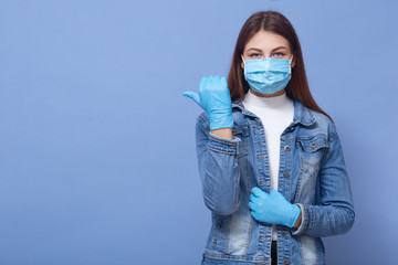 Image of brunette Caucasian woman with long hair, wearing medical face mask and disposable gloves...