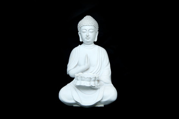 The white statue of the calm sitting buddha isolated in a black background. 