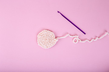 Unfinished knitting project with crochet hook. Pink woman concept. Copy space, top view